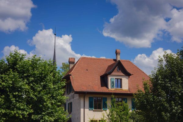 Maison en pierre, ciel bleu et arbres verdoyants.